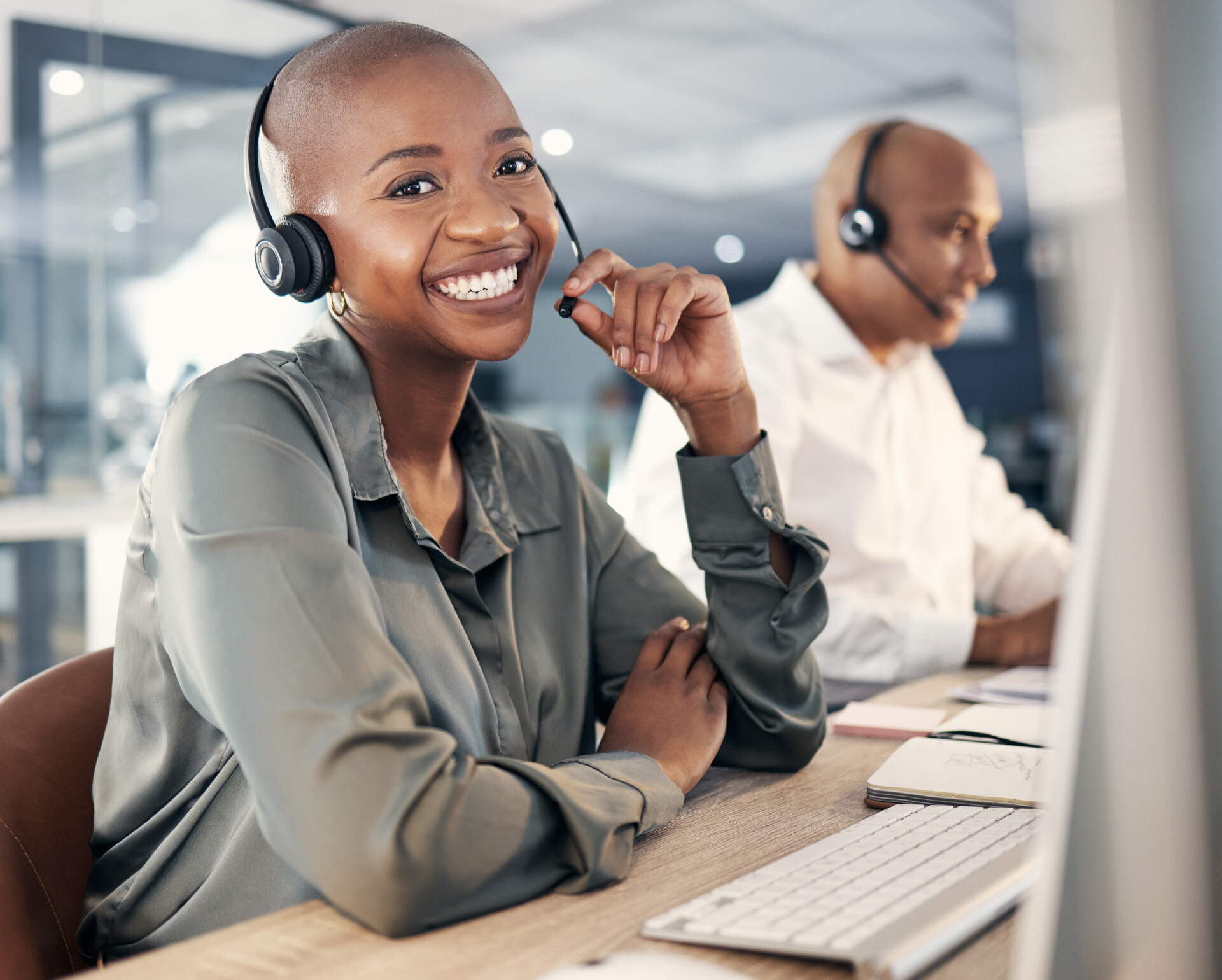 Portrait of happy young african american call centre telemarketing agent talking on a headset while.